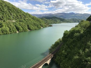 Scenic view of river by mountains against sky