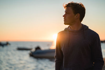 Man standing by sea against clear sky during sunset