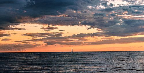 Scenic view of sea against dramatic sky during sunset