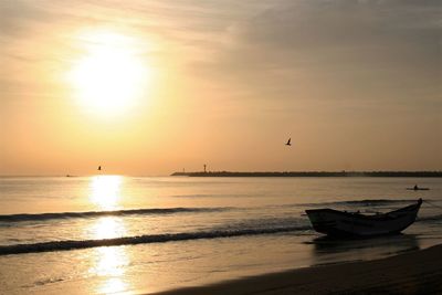 Boat moored in sea against sky during sunset