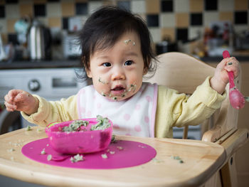 Portrait of cute girl with messy face having food at home
