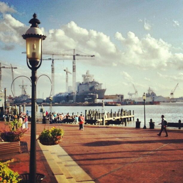 water, sky, street light, transportation, built structure, architecture, cloud - sky, building exterior, nautical vessel, sea, lighting equipment, river, men, mode of transport, travel, city, incidental people, harbor, person