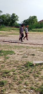 People walking on field against sky