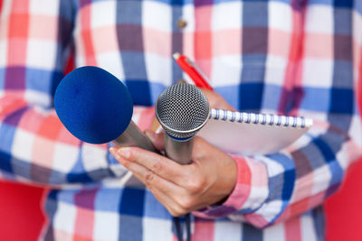 Midsection of man holding microphones