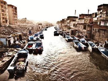 Boats in canal amidst buildings against clear sky