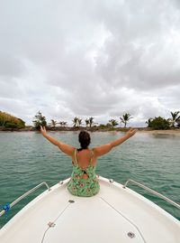 Rear view of woman on boat in sea against sky