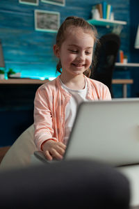 Smiling girl using laptop at home