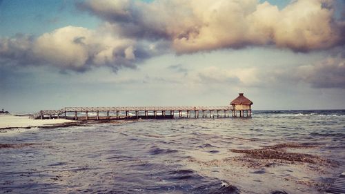 Pier on sea against cloudy sky