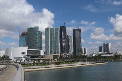 Modern buildings by river against sky in city
