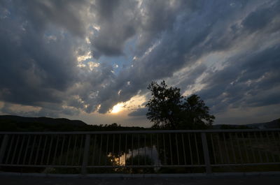 Trees on landscape against sky at sunset
