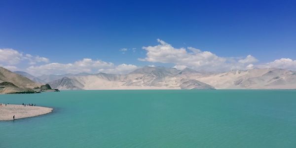 Scenic view of sea and mountains against blue sky