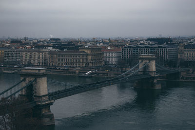 Bridge over river in city against sky