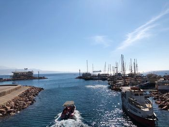 Boats moored at harbor against blue sky