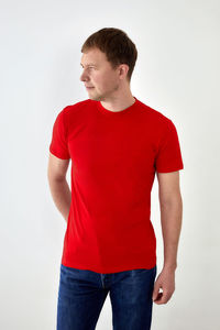 Young man looking away while standing against white background