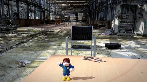 Figurine by chair against abandoned factory
