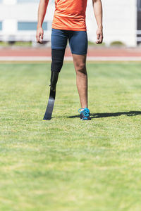 Low section of athlete with prosthetic leg standing on field