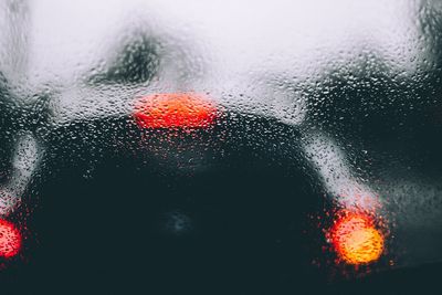 Full frame shot of wet windshield against illuminated tail lights