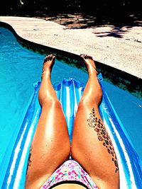 Low section of woman relaxing in swimming pool