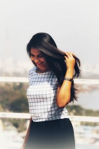 Beautiful young woman standing against sky