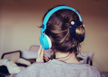 Rear view of woman listening music against wall