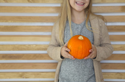 Woman holding pumpkin while sitting on staircase