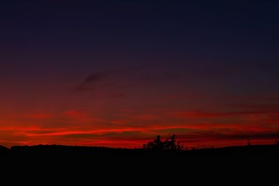 Silhouette landscape against dramatic sky during sunset