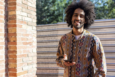 Portrait of young man standing against brick wall