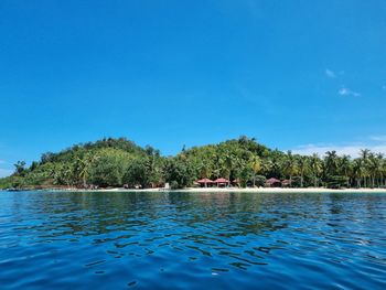 Swimming pool by lake against clear blue sky