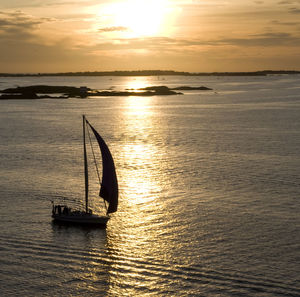 Silhouette boat in sea against sky during sunset