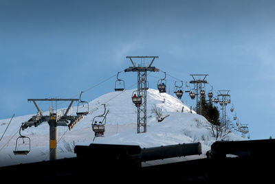 Ski lift on snow covered mountain against sky