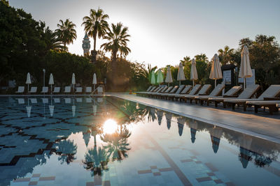 Loungers and umbrellas arranged at poolside in tourist resort during summer