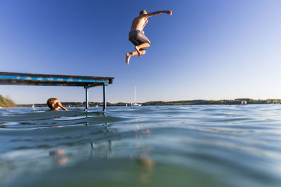 Man jumping in sea against clear sky