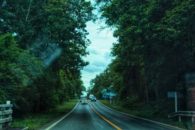 Road amidst trees against sky