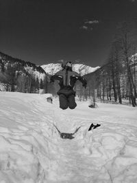 Man jumping over snowy land against sky