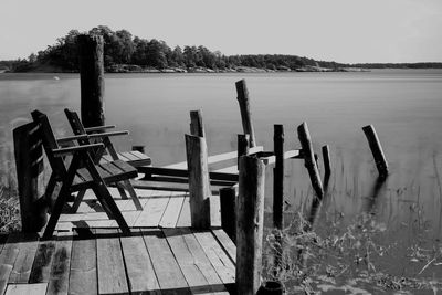 Wooden posts on table by lake against sky