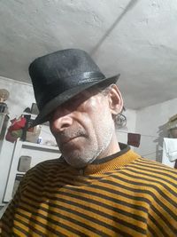 Portrait of man wearing hat against wall