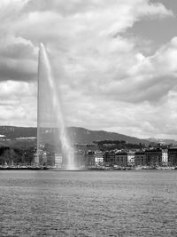 Fountain in city against cloudy sky