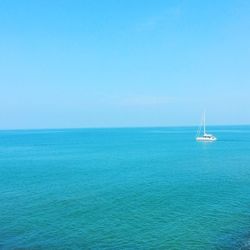 Sailboat sailing in sea against clear blue sky