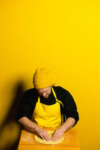 Chef preparing food against yellow background