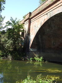 Arch bridge over river against sky