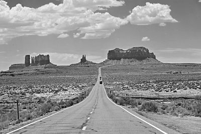 Road passing through landscape against cloudy sky