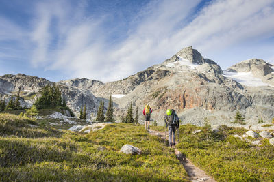 Rear view of people walking on mountain against sky