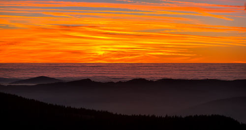 Scenic view of silhouette mountain against orange sky