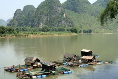 Boat houses floating on water against rocky mountains