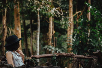 Rear view of woman standing amidst trees in forest
