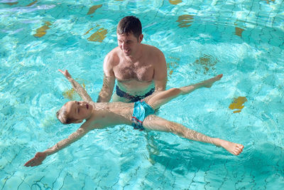 Happy father and son swimming lesson in pool. child learning swim. family, parenthood, sport concept