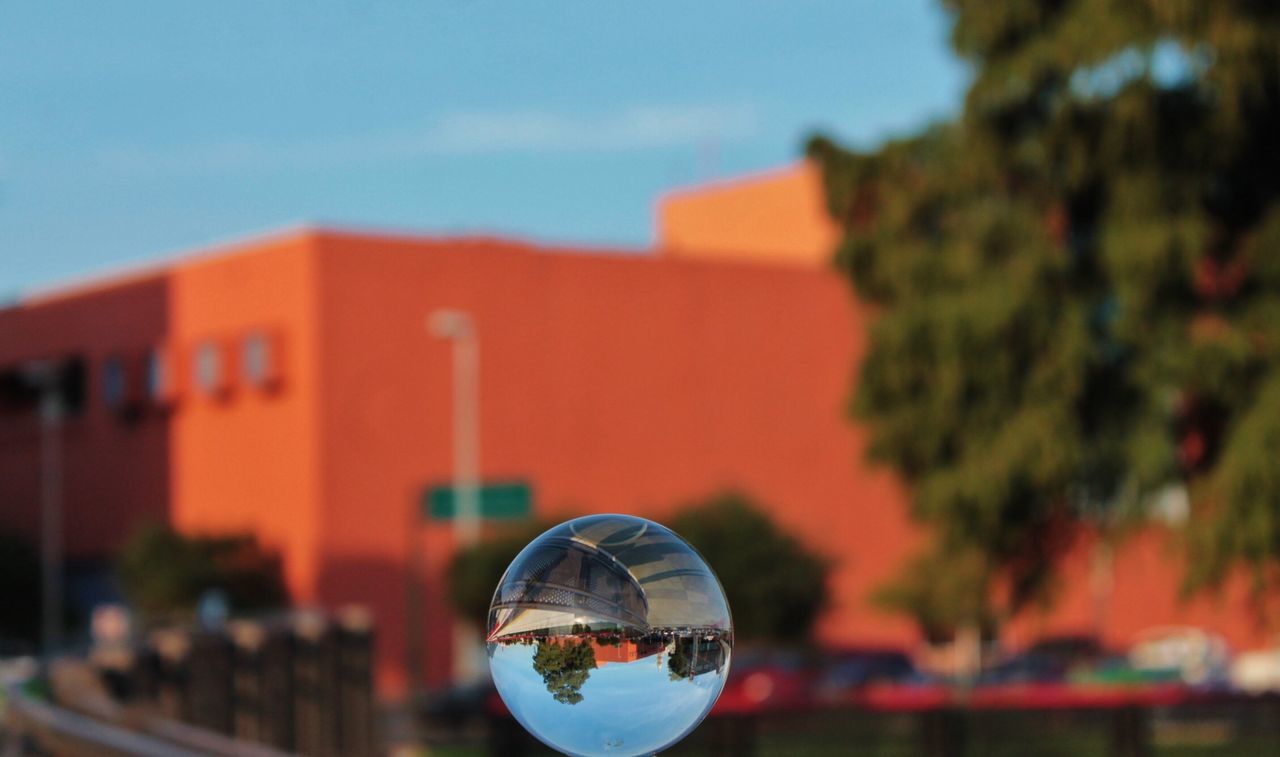 building exterior, architecture, focus on foreground, built structure, sky, transportation, close-up, selective focus, outdoors, tree, circle, red, no people, dusk, day, cloud, reflection, house, city, mode of transport