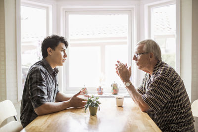 Side view of grandfather and grandson communicating while having coffee