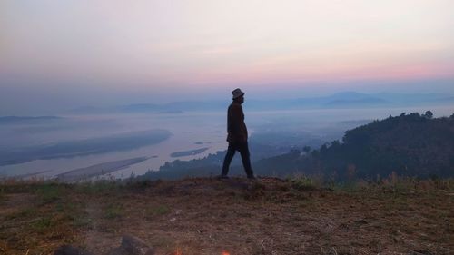 Man standing on land against sky during sunset