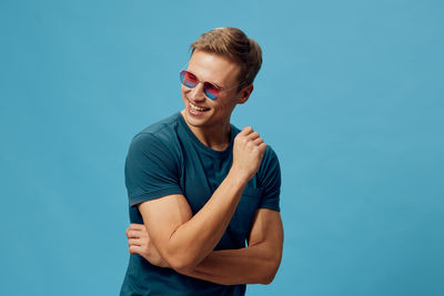 Portrait of young man standing against blue background